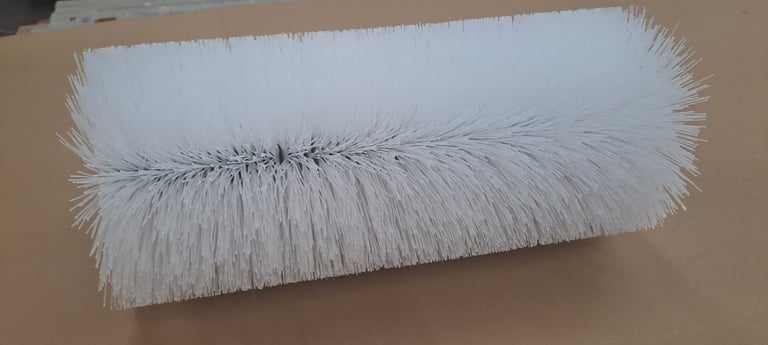 White cylindrical brush roll with dense bristles on a tan background