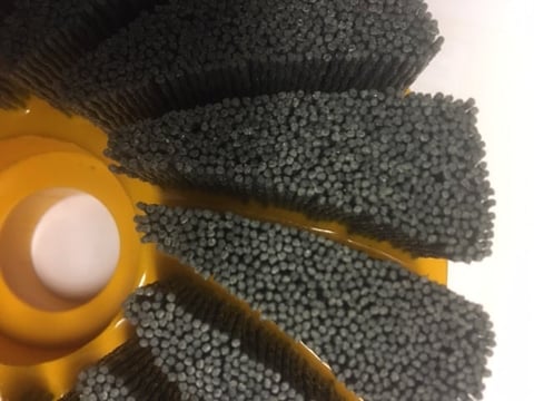 Close-up of yellow cleaning brushes with gray bristles arranged in a fan pattern