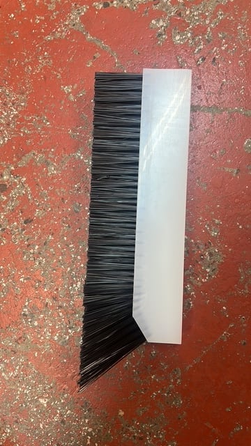 Paint brush with black bristles and white handle resting on a weathered red textured surface