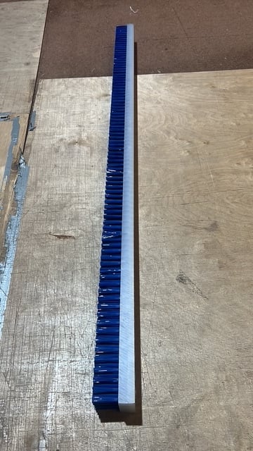 Long blue flexible cable conduit or tubing lying on wooden flooring