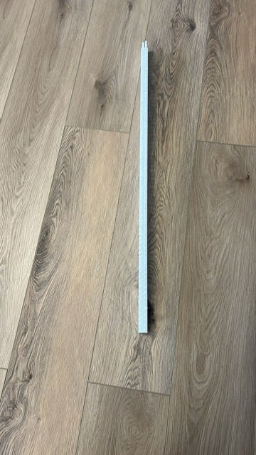Long white fluorescent tube light lying on wood-grain laminate flooring