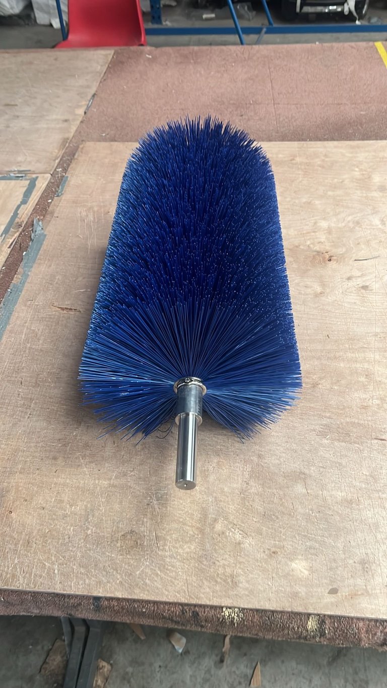 Blue cylindrical brush head with metal shaft displayed on wooden surface in warehouse setting