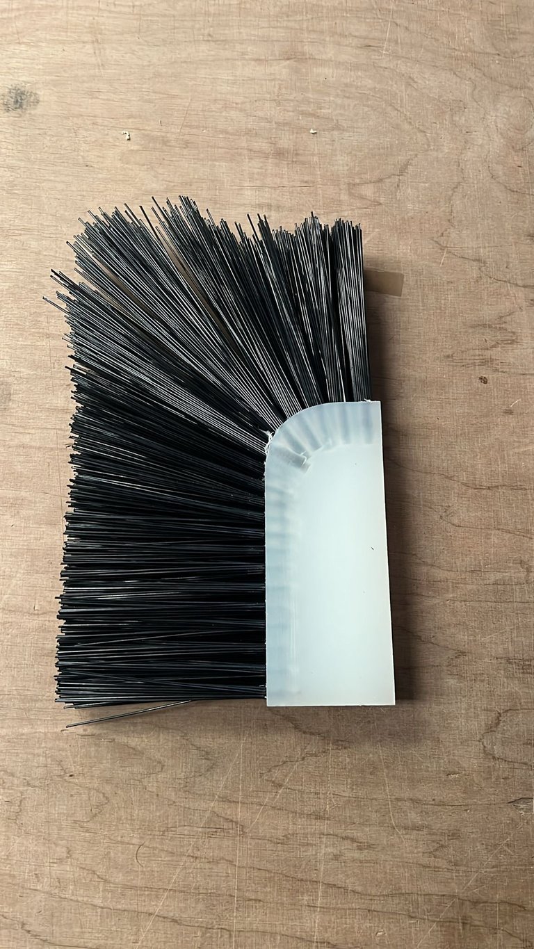 Black bristled hand brush with white rectangular handle on wooden surface