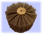 Top view of a round brown-bristled scrub brush with a yellow center on a light purple background