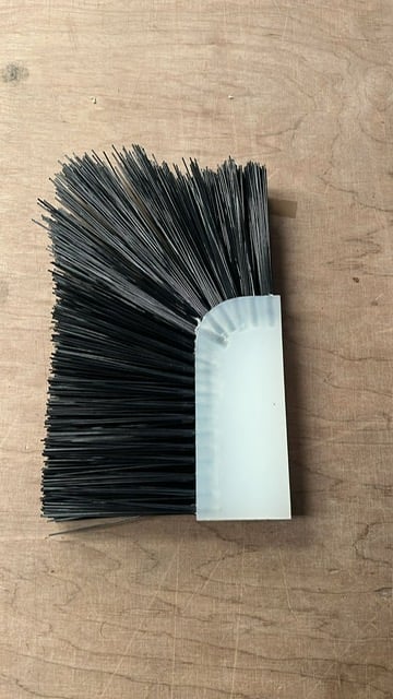 Black bristle brush with white handle viewed from above on wooden surface