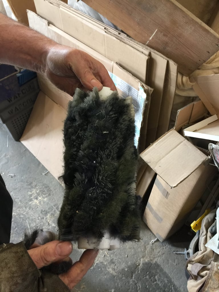 Person holding a black fluffy cat in a room surrounded by cardboard boxes