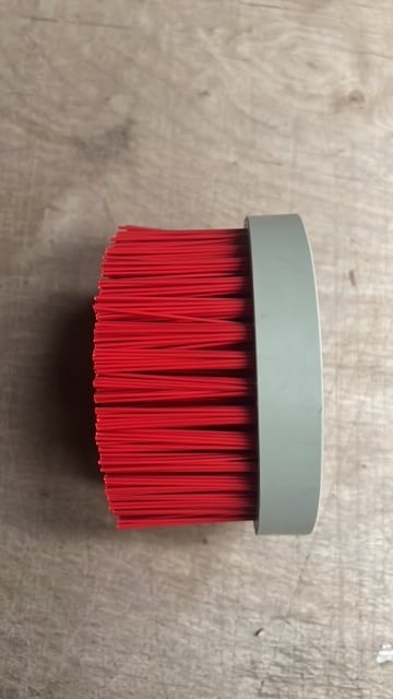 Red cylindrical brush with gray band on wooden surface