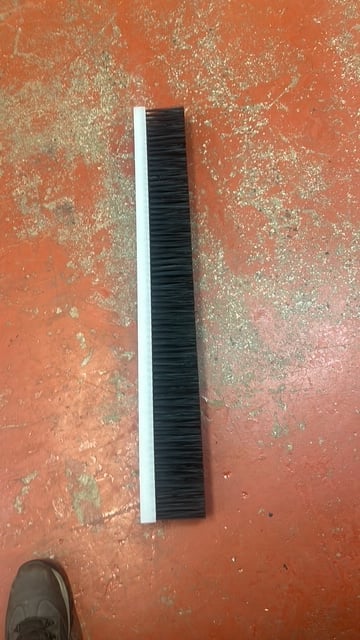 Black and white push broom lying on weathered orange textured floor