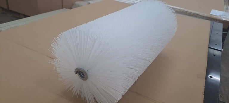 White cylindrical brush with bristles on cardboard surface, industrial cleaning tool