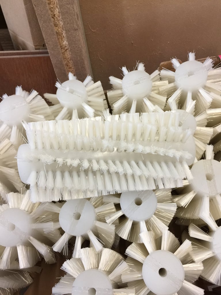 Collection of white nylon brush heads with bristles for industrial cleaning equipment, displayed on a work surface