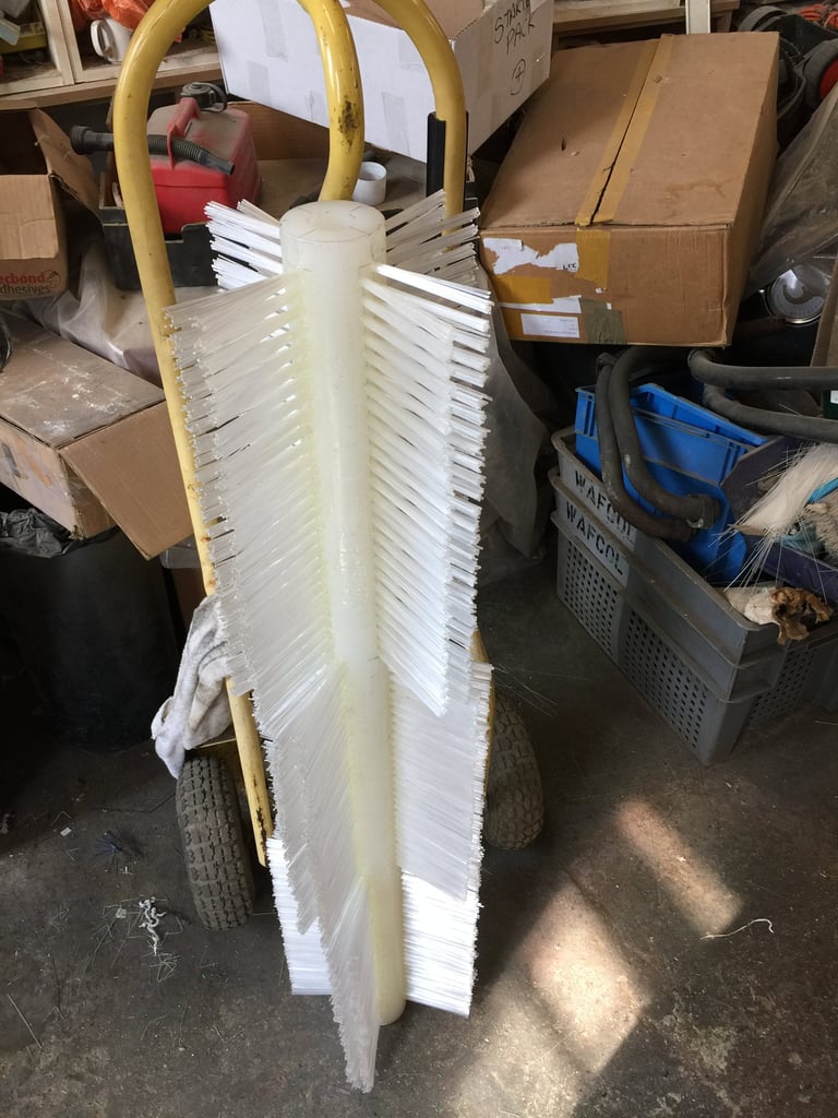 Stack of white plastic plates with yellow handles leaning against cardboard boxes in a storage area