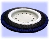 Round industrial brush with dark blue bristles and white center disc, used for surface cleaning
