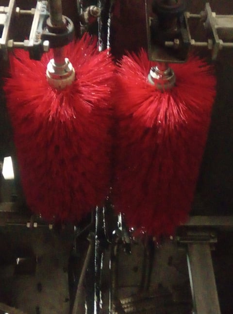 Two red decorative pom-poms with metallic centers hanging from industrial machinery or equipment