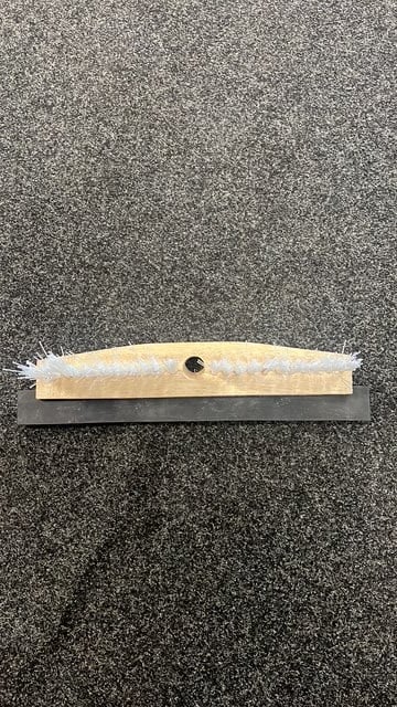 Squeegee with white rubber blade and black handle on textured gray background