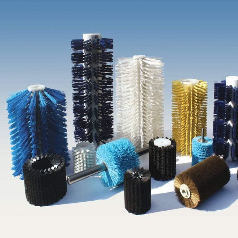 Collection of industrial cylindrical brush rollers in various colors including blue, black, white, yellow, and brown arranged on white surface