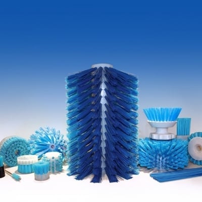 Collection of blue cleaning brushes arranged around a tall cylindrical brush, displayed against a white background and blue sky