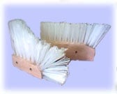 Three paintbrushes with white bristles and wooden handles arranged against a light blue background